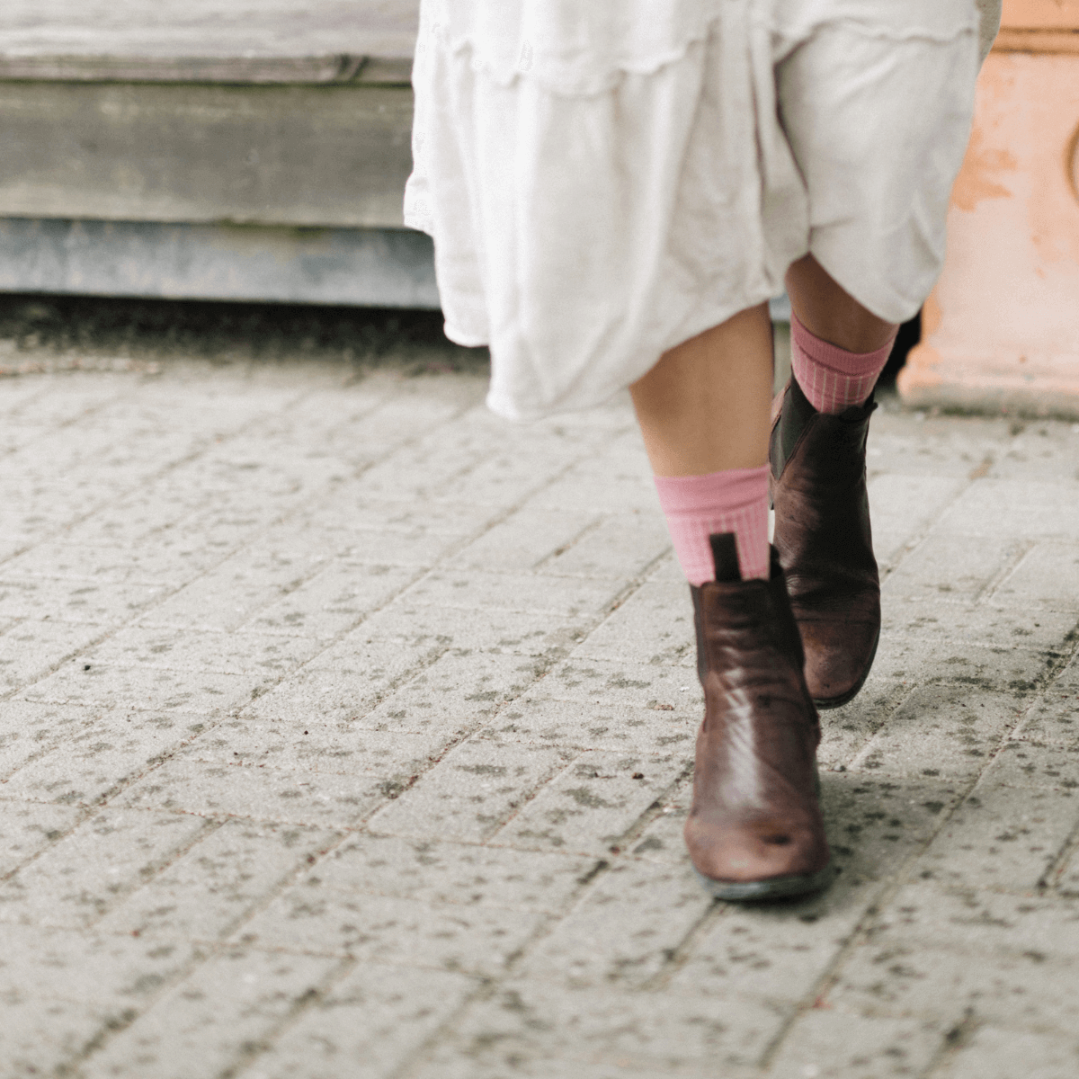 Woman wearing Merino Wool Crew Socks in pink while walking on a street.