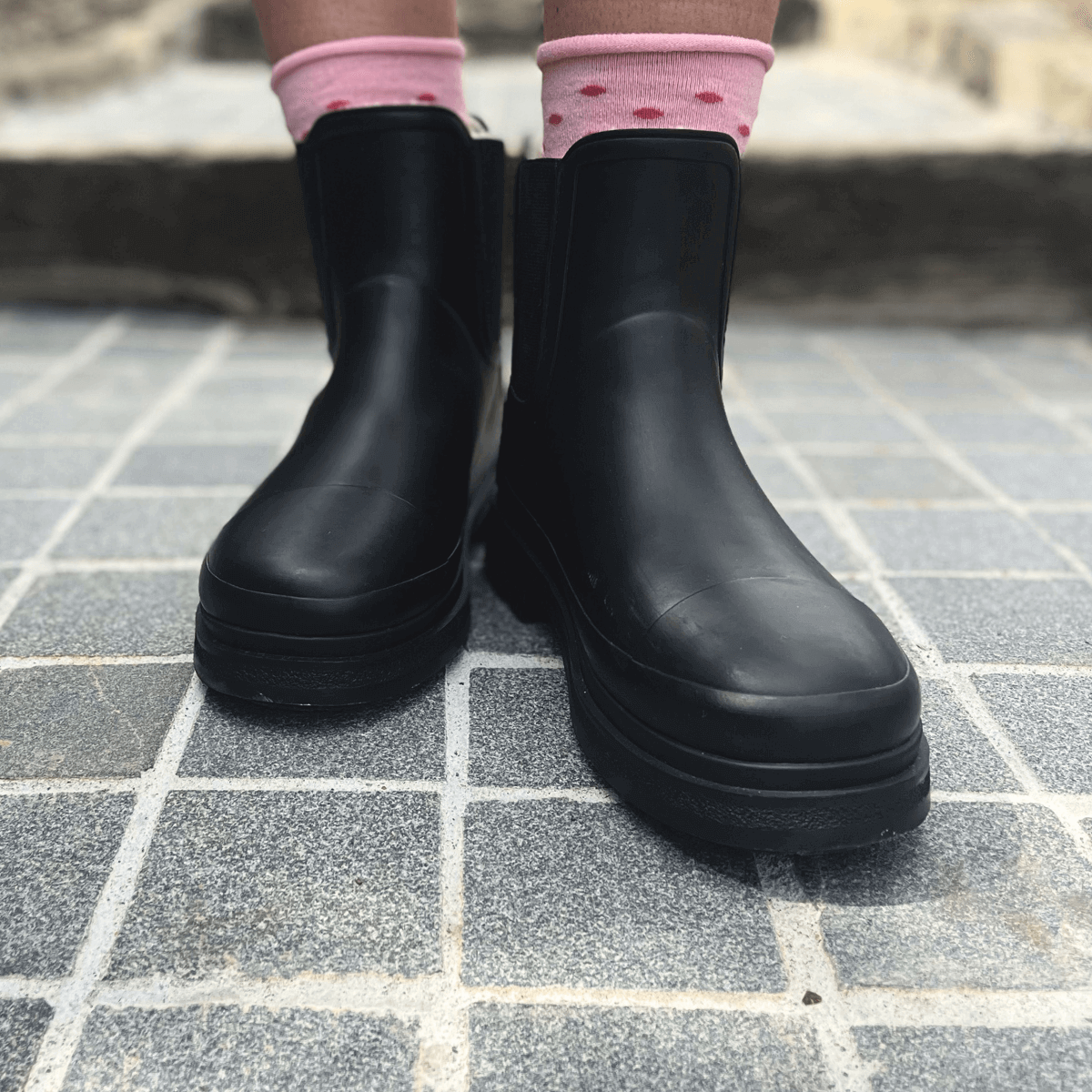Merino Wool Crew Socks | WOMAN | Maggie worn with black rubber boots on a stone pavement.
