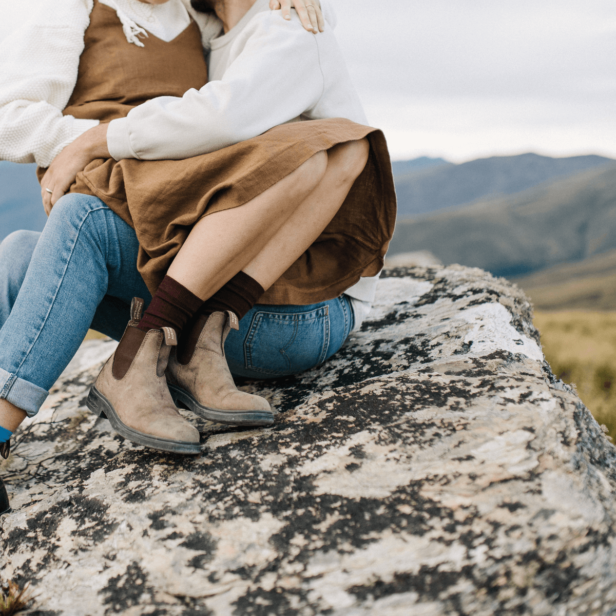 Merino Wool Crew Socks for Woman in Fig, worn with casual outfits while sitting on a rocky surface outdoors.
