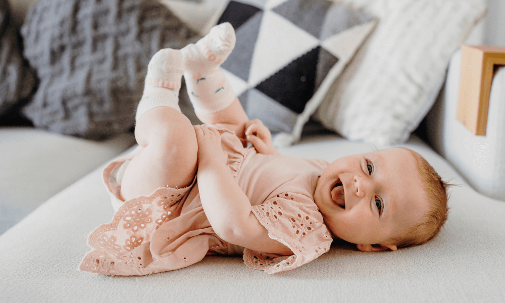 Baby wearing merino socks , smiling and laying on a couch.