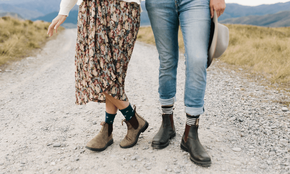 Australians need Warm Socks, featuring a couple walking in stylish boots and colorful socks on a gravel path.