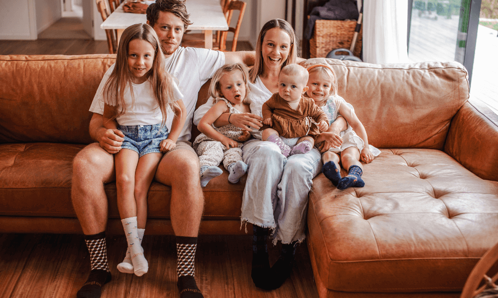 Family enjoying a cosy moment on the couch with children wearing Lamington Merino Socks