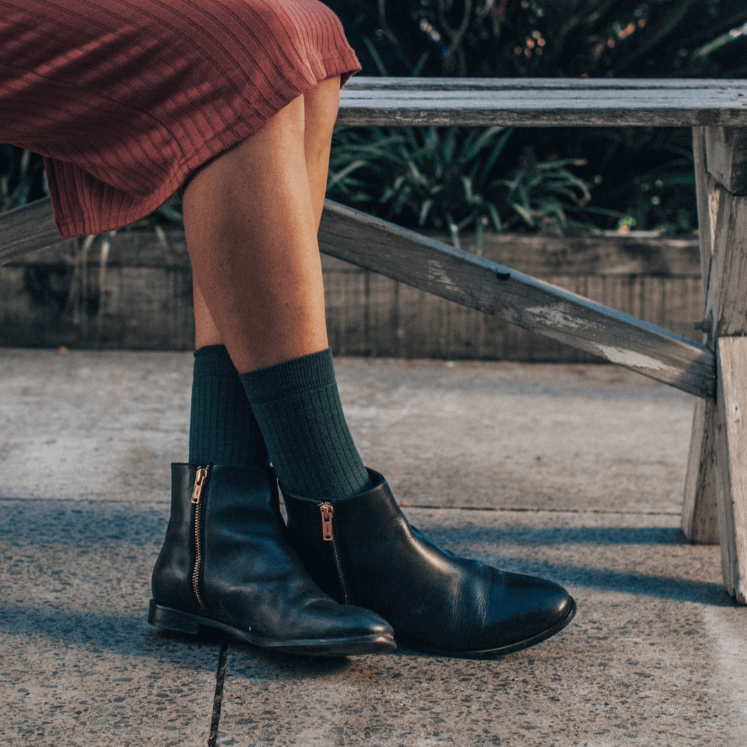Woman wearing Merino Wool Crew Socks with black ankle boots, showcasing the deep mossy green color.